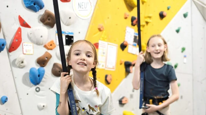Zwei Mädchen kurz vor dem start in die Kletterwand - lachen freudig in die Kamera | © DAV / Jens Klatt