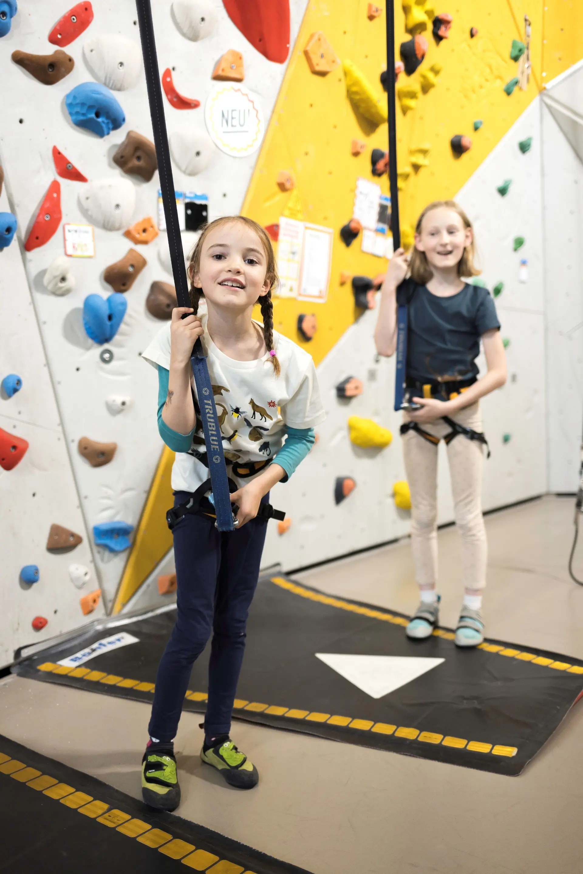 Zwei Mädchen kurz vor dem start in die Kletterwand - lachen freudig in die Kamera | © DAV / Jens Klatt