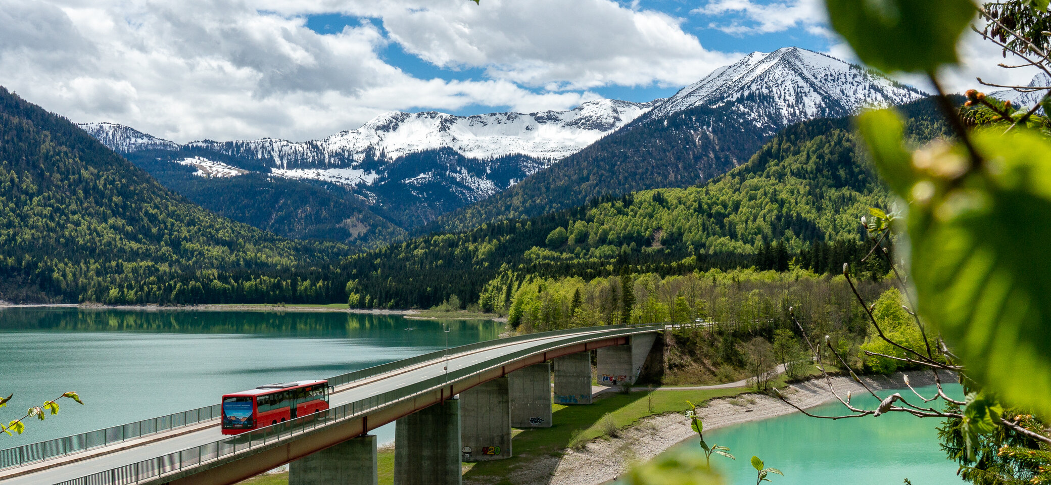 Der Bergbus des Deutschen Alpemvereins fährt über eine Brücke in die Alpen | © DAV/Tobias Hipp