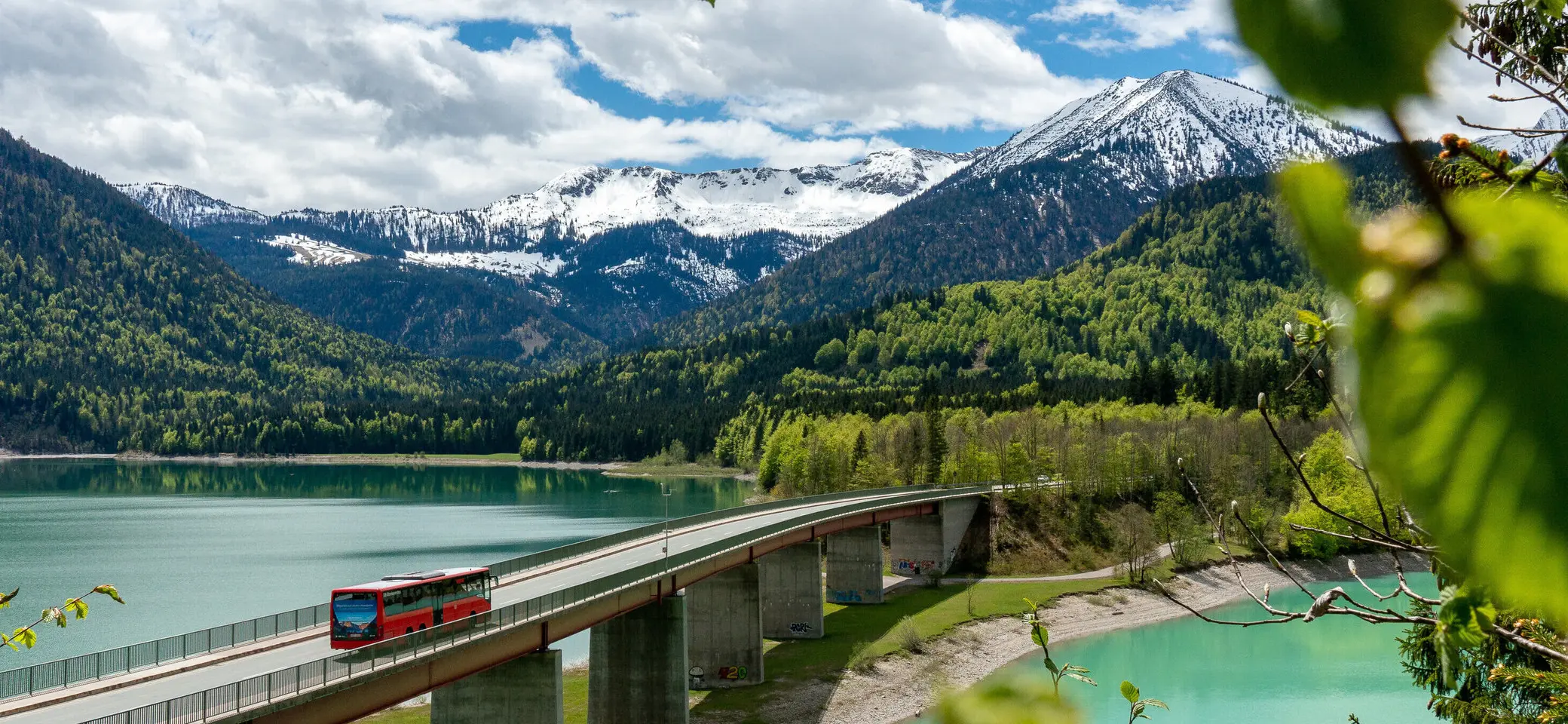Der Bergbus des Deutschen Alpemvereins fährt über eine Brücke in die Alpen | © DAV/Tobias Hipp